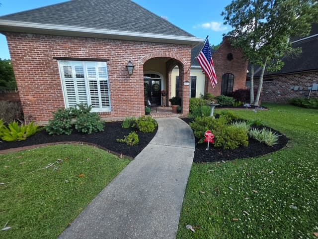 Brick home entry with black mulch beds and trimmed boxwoods Louisiana