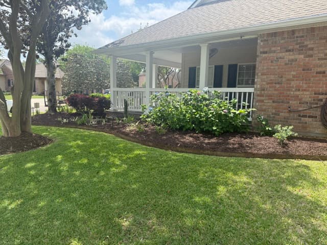 Refreshed flower bed with hydrangeas and fresh mulch beside porch Louisiana