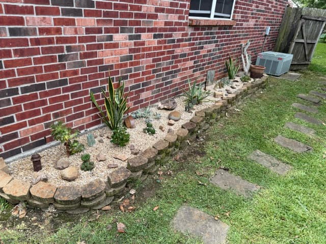 Succulent rock garden with stacked stone border along brick wall Louisiana