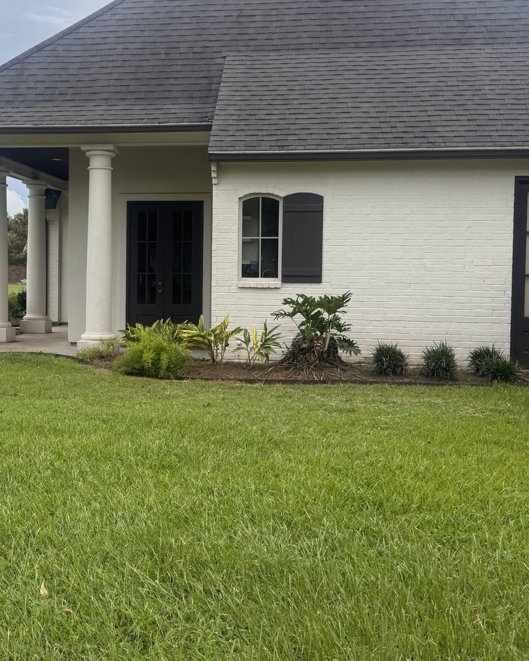 The same entry after service: clean mulched bed, tidy shrubs and a sharp walkway edge